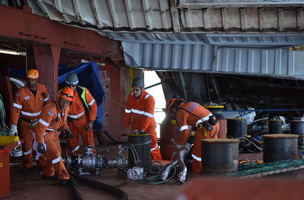 Salvors aboard Rena work to attach oil pumping hoses on deck