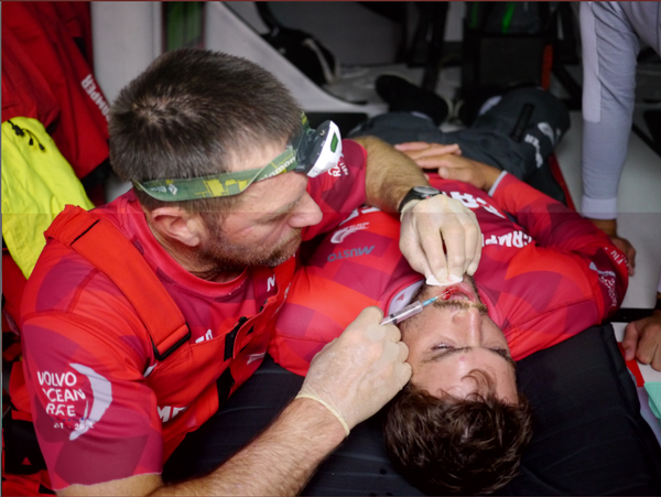 Tony Rae injects local anesthetic into Mike's severed lip and broken tooth before suturing.