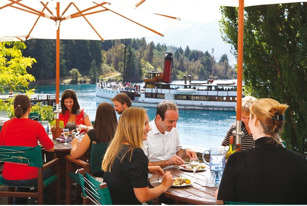 Visitors dining at Walter Peak with TSS Earnslaw in background.