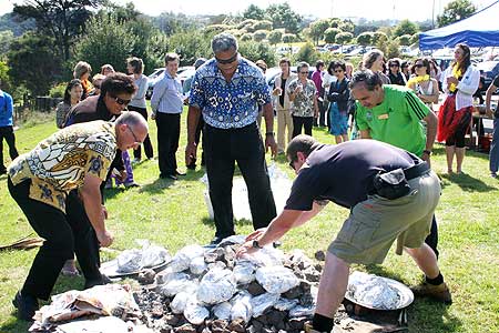 Ben Taufua (centre), national project manager for the Pasifika@Massey strategy, oversees the retrieval of cooked meats and vegetables from the umu while staff stand by for the feast.